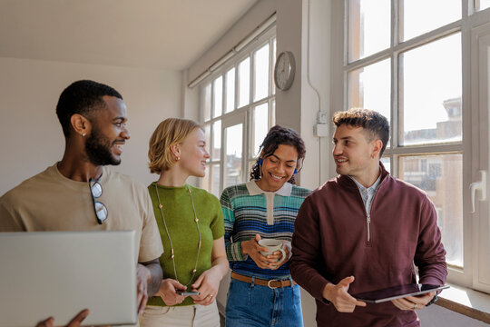 Diverse startup team walking and talking in modern office