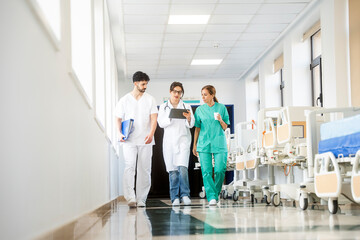 Medical team walking through hospital corridor using tablet