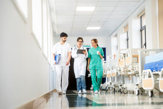 Medical team walking through hospital corridor using tablet