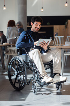 Man in wheelchair using tablet in a modern workspace