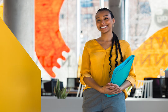 Confident professional woman holding folder in modern office