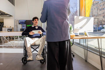 Collaborative office meeting with wheelchair user and tablet