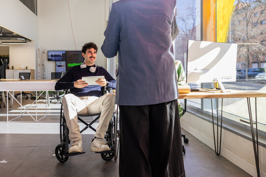 Collaborative office meeting with wheelchair user and tablet