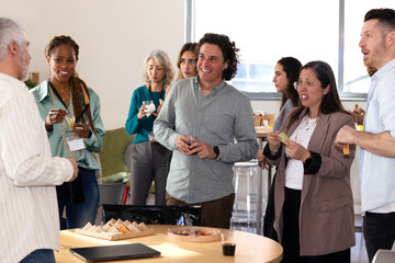 Diverse group enjoying casual office gathering with snacks