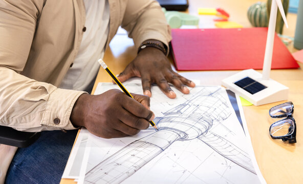 Architect drafting blueprint of wind turbine on desk