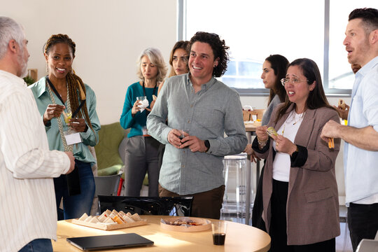 Diverse group enjoying casual office gathering with snacks - Powered by Adobe