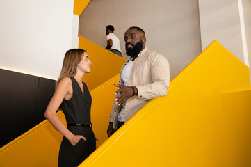 Colleagues Discuss Work on Yellow Staircase in Modern Office