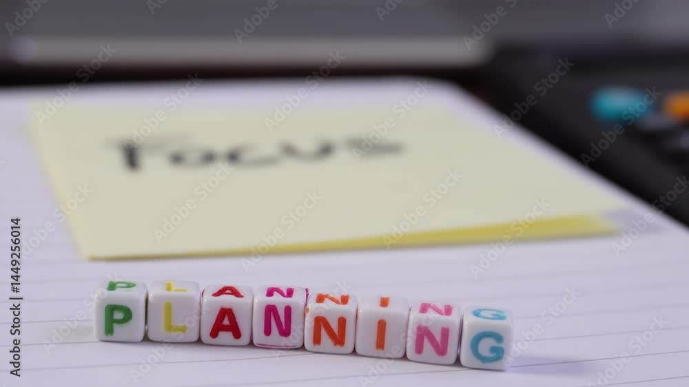 Poster focus and blur with a white notebook with a yellow sticky note that says focus and a cube of letters