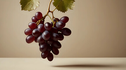 A cluster of ripe purple grapes hanging elegantly against a soft beige background, ideal for food-related projects
