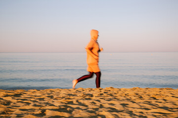 Woman jogs along the beach at sunrise