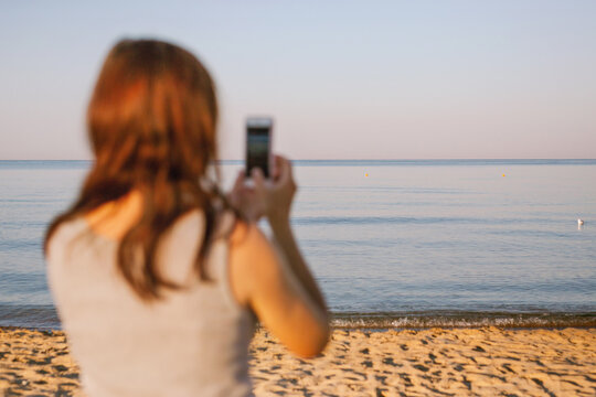 A woman filming the sea on her phone