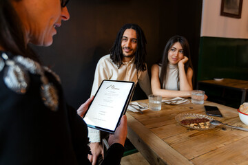 Wedding planner discussing menu option to young couple in restaurant