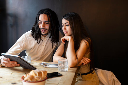 Young couple checking restaurant menu on tablet device