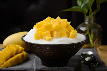 Mango shaved ice in a black bowl, a summer dessert
