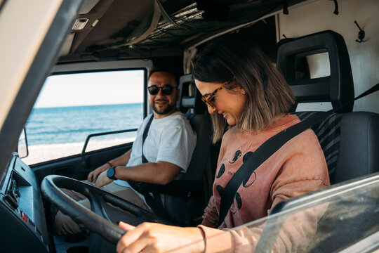 Couple driving camper van on the beach, enjoying road trip