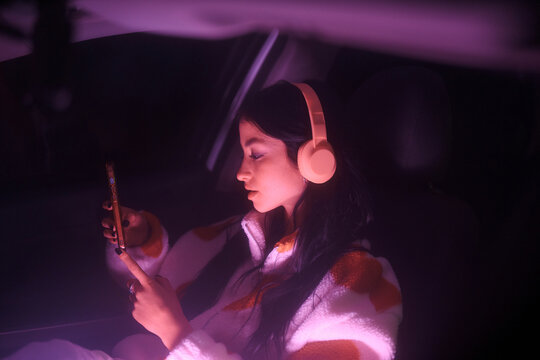 Night colorful portrait of passenger woman with phone and headphones