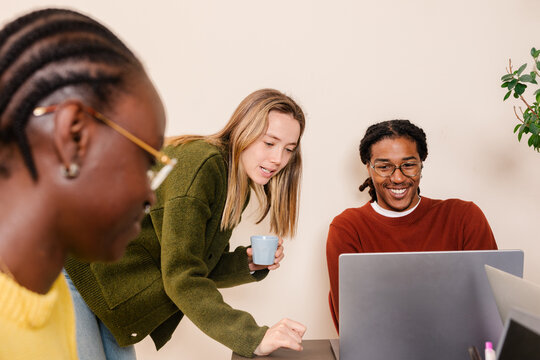 Work team having fun while reviewing paperwork on laptop computers