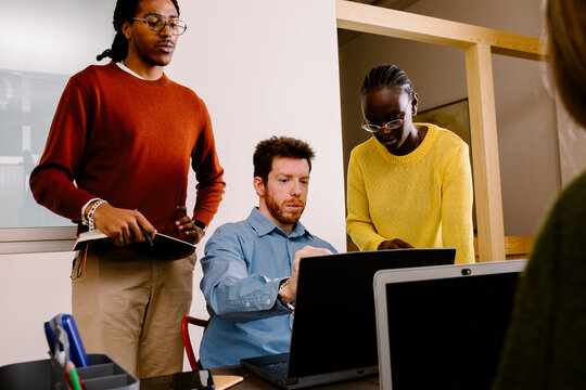 Professionals use a laptop to forward contracts during a work session