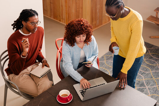 Slightly overhead view of a small team working and drinking coffee
