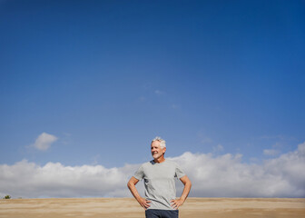Confident Senior Outdoors Under a Clear Blue Sky with Hands on Hips
