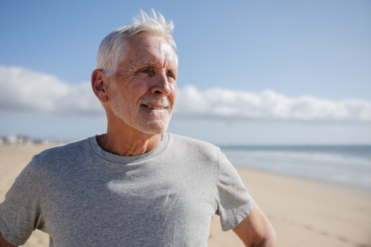 Senior Man Smiling on a Peaceful Beach with Clear Blue Sky