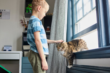 Boy with eczema in his room playing with cat