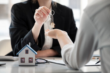 Close-up shot of a real estate agent or realtor meeting with her client, giving new house key to...