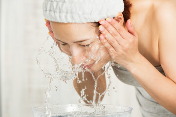 アジア人の若い女性は洗顔しています.