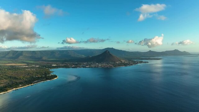 Wide aerial view of beach, coastal town, and mountains at sunset in Flic en Flac