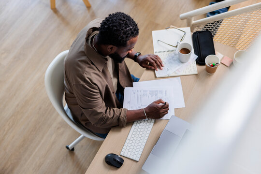 High angle view of man doing paperwork at desk in home office