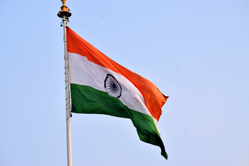 Indian National Flag Waving Against Clear Blue Sky,A high-resolution image of the Indian national flag (Tiranga) gracefully waving in the wind against a clear blue sky. 