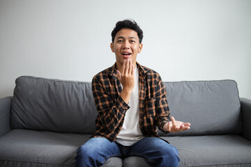 Man showing THANK YOU gesture in sign language while sitting on a couch