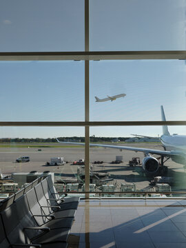 Airport indoor hall with glass wall and view of  airplane taking off 