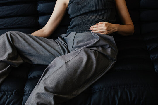 Anonymous woman in grey clothes holding hand on her belly 