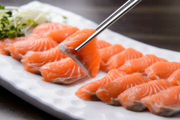 Holding a piece of sashimi with chopsticks
