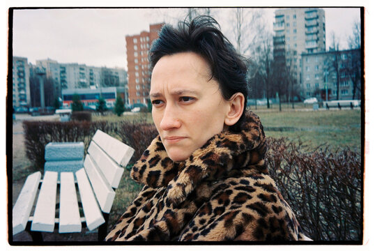 Woman in leopard coat sits on a bench in chilly weather