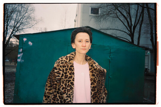 Woman in leopard print coat stands in front of graffiti wall