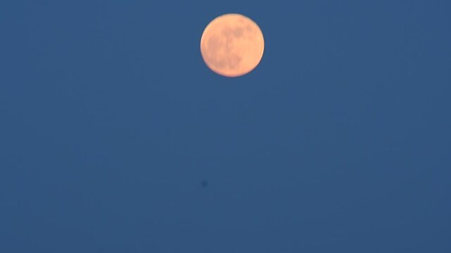A funny `dancing` full moon in a beautiful cloudless evening sky