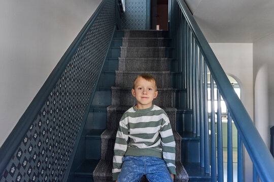 Little boy sits on the staircase at his house