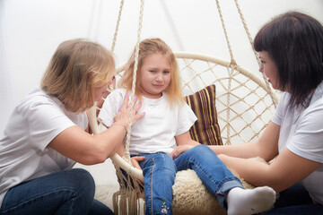 Two adults support a child during a therapeutic session in a cozy, indoor space focusing on...