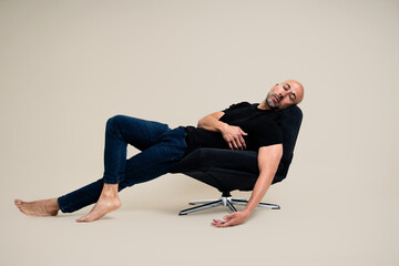 Man reclining on a black chair with eyes closed
