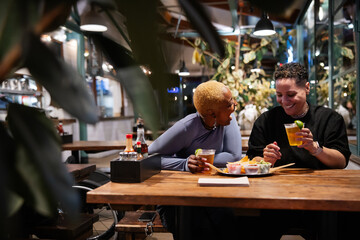 Friends Sharing Drinks and Food at an Outdoor Cafe During Evening