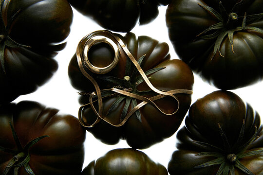 Dark Tomatoes Adorned with Elegant Golden Accessories
