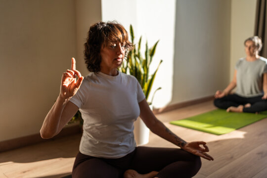 Mature women practicing gyan mudra yoga position during group lesson