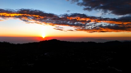 sunrise in the mountains with golden gradation of light on dark textured clouds