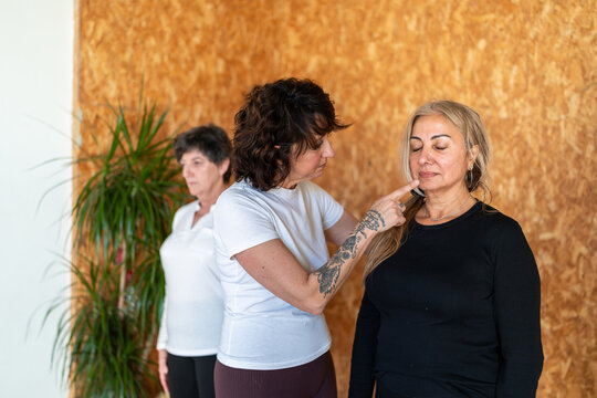 Yoga teacher adjusting student's posture during face yoga exercise
