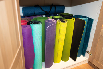 Colorful yoga mats stored in wooden cabinet promoting relaxation