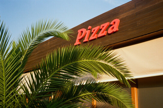 A pizzeria near palm tree in the dawn sunlight. 