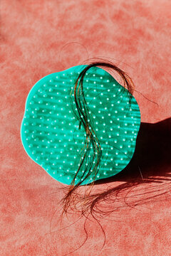 green scalp brush with a lock of hair