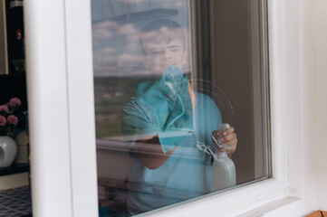 12-year-old boy doing household chores at home: cleaning windows. Daily routine of a responsible...